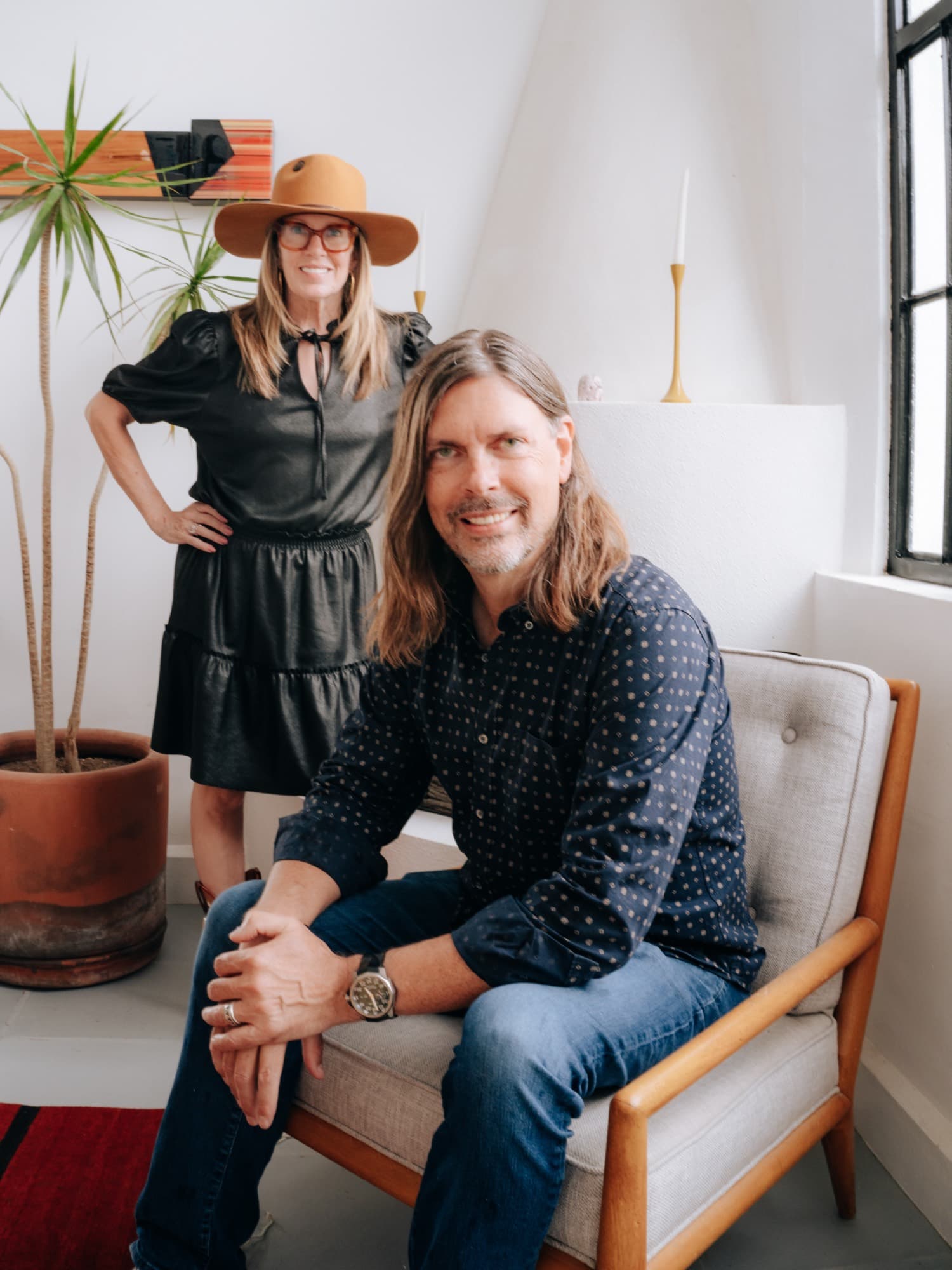 Tiffany Paige standing behind Mike Biersma, who is seated in a mid-century chair