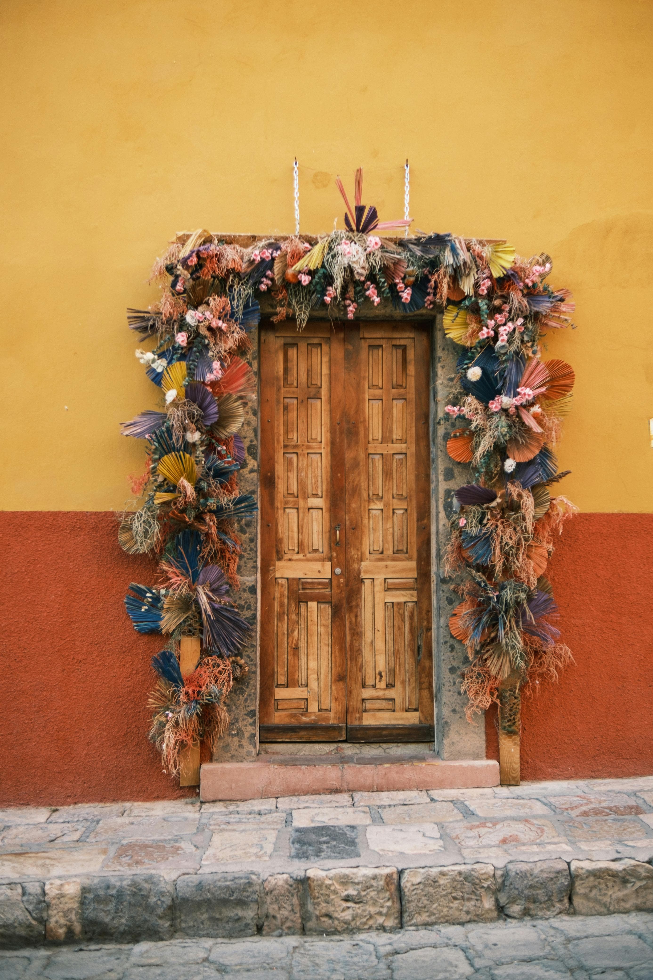 Decorated wooden doorway on a yellow wall in San Miguel de Allende