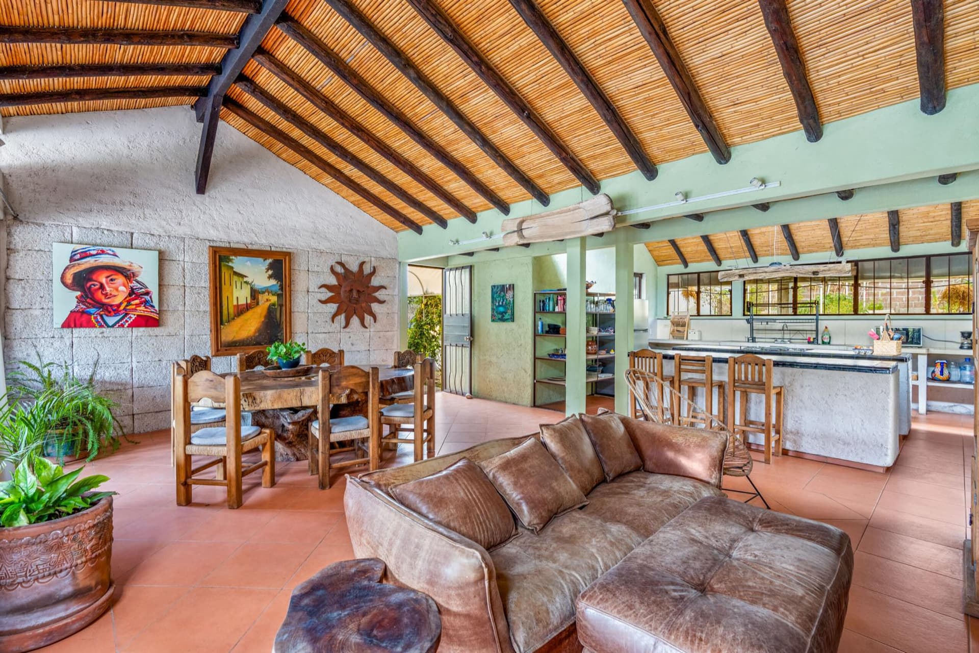 An open living and dining space at Queerhaven beneath a carrizo and beam ceiling