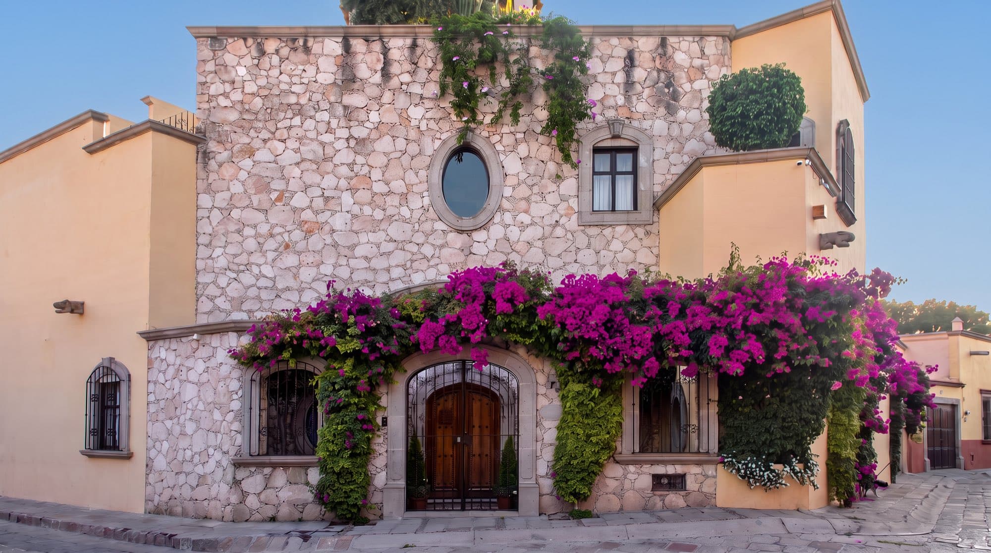 A stone colonial home with bougainvillea on a cobblestone corner in Guadiana, San Miguel de Allende