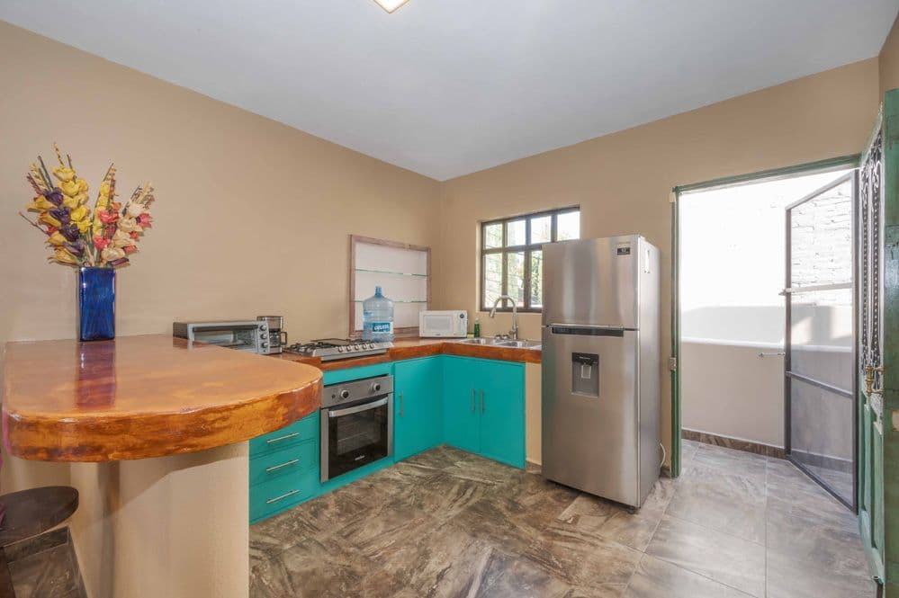 Duplex Fray Bartolome — Independencia, San Miguel de Allende — photo 2 — vibrant turquoise kitchen, sun-drenched elegance