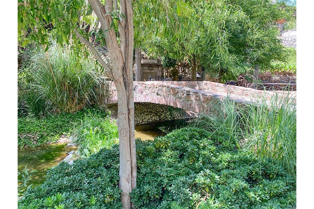 Casa Huerta La Antigua — Antigua Residencial, San Miguel de Allende — photo 30 — charming arched bridge, verdant waterside gardens